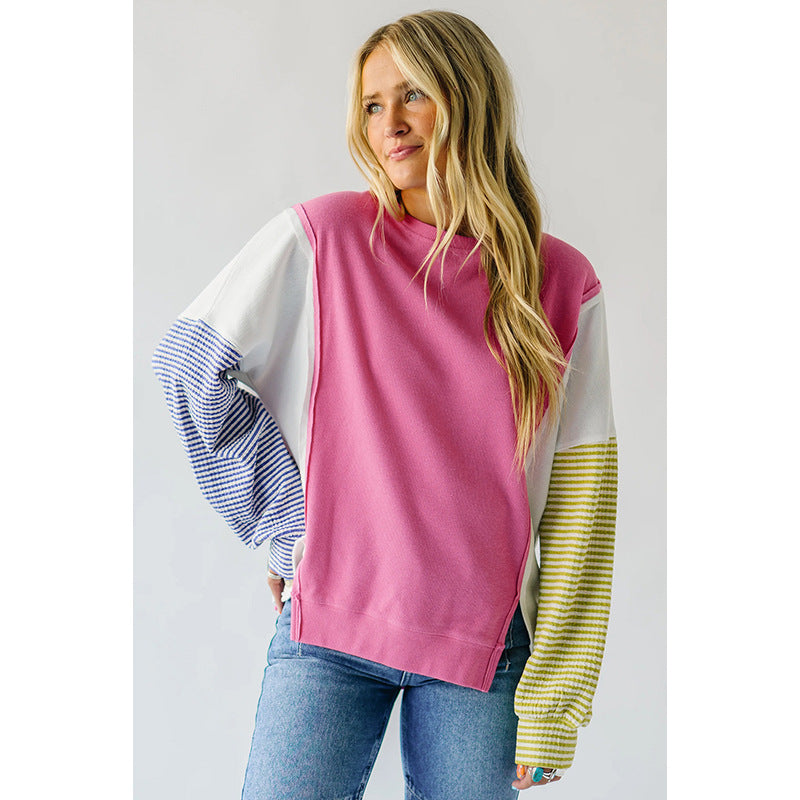 Pink and yellow striped sweatshirt displayed on a hanger against a neutral background.
